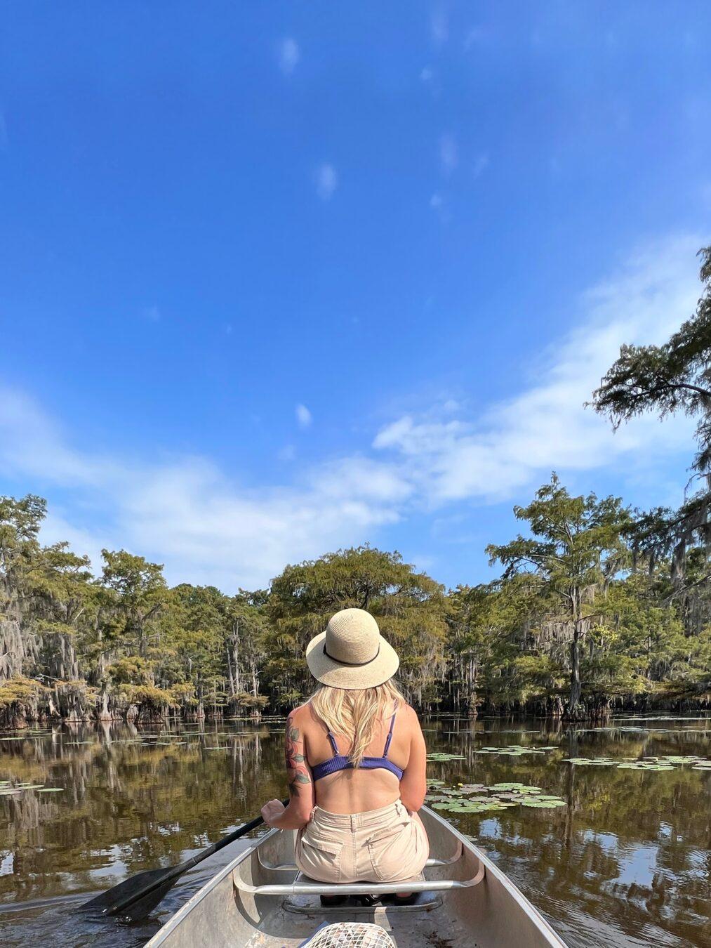 Girl canoeing with straw hat, surrounded by cypress trees at caddo lake state park