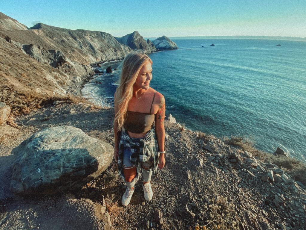 Girl standing at Big Sur in this post about tanning oils.